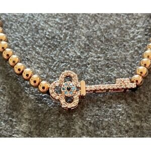 Gold beaded‎ bracelet with a crystal key charm.